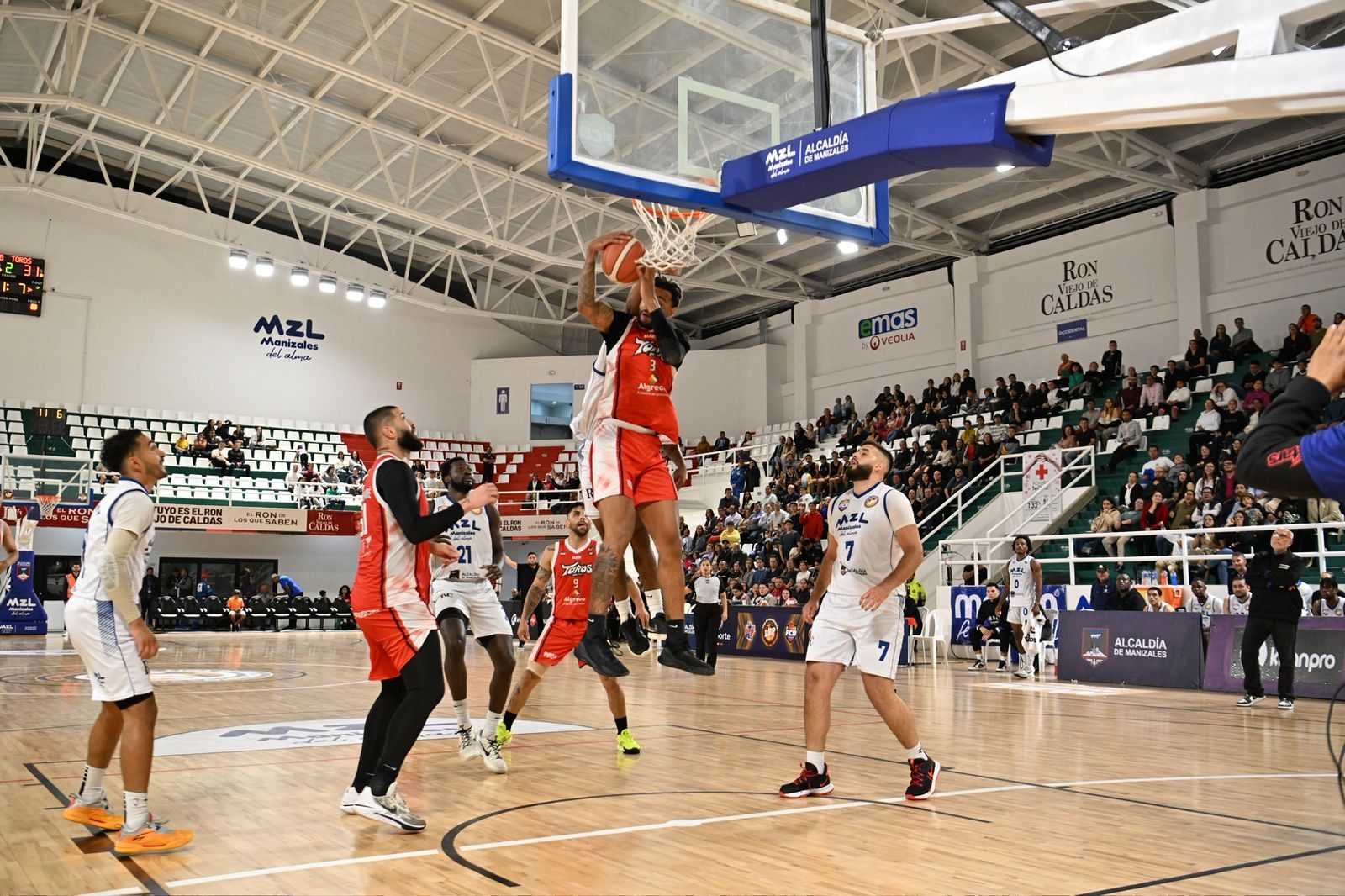 Acción de juego de baloncesto profesional con vallas LED de patrocinadores activas en la cancha.